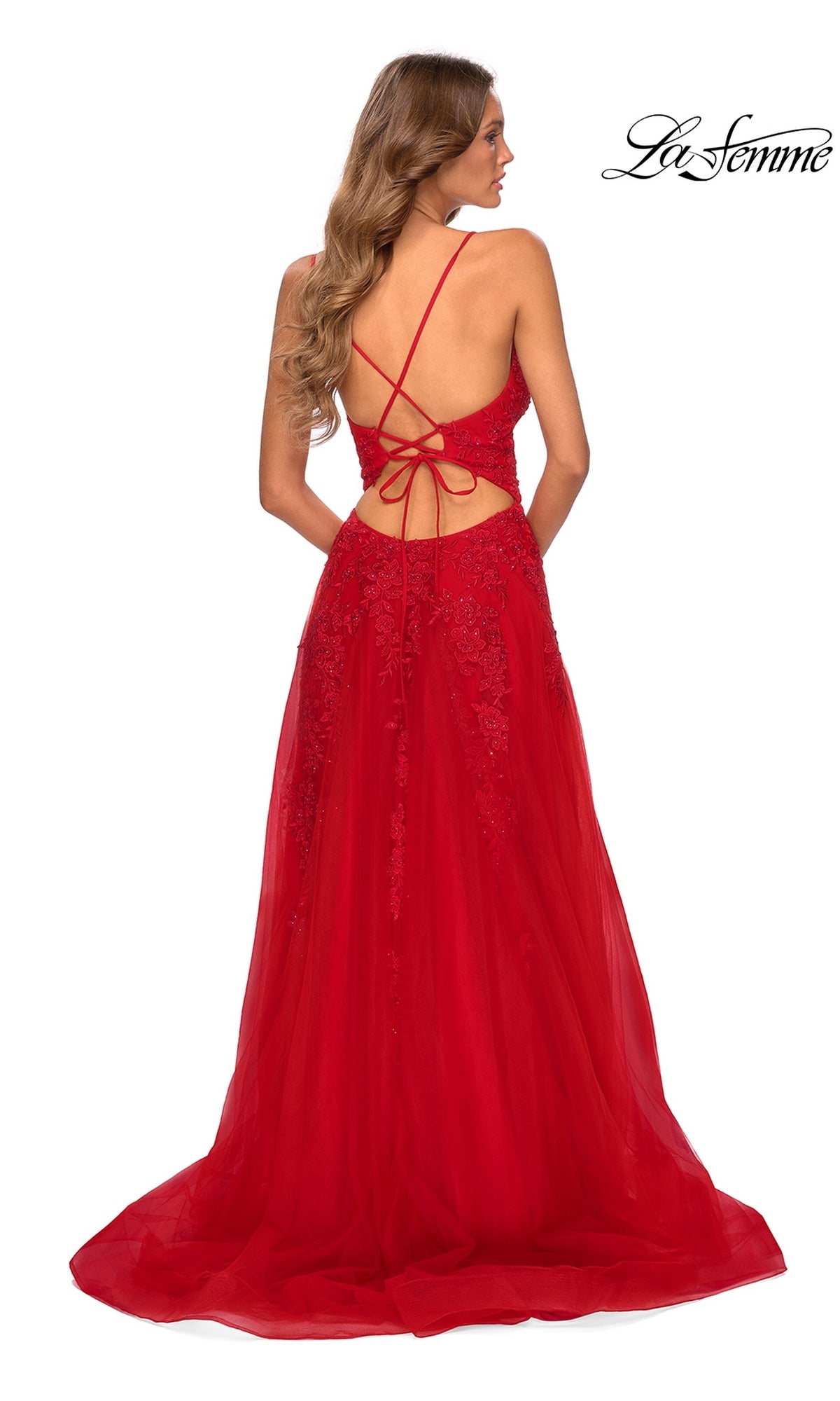 A woman models the Strappy-Back Long Prom Dress: La Femme 28985, showcasing its lace details and open back with crisscrossed straps as she stands facing away from the camera.
